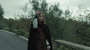 Bulutlu bir günde kırsalda pelerinli genç bir kadın..