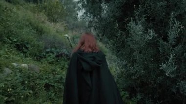 Bulutlu bir günde kırsalda pelerinli genç bir kadın..