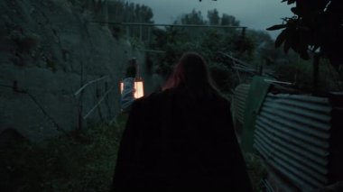 Bulutlu bir günde kırsalda pelerinli genç bir kadın..