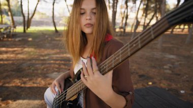 Sahilin yanındaki doğada bas gitar çalan bir kız..