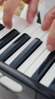 Beyaz gömlekli çocuk dışarıdaki doğada piyano çalıyor..