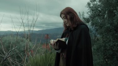 Bulutlu bir günde kırsalda pelerinli genç bir kadın..