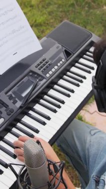 Beyaz gömlekli çocuk dışarıdaki doğada piyano çalıyor..