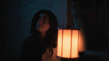 Gizemli genç kadın pelerin ve fenerle bir köyün sokaklarında yürüyor..