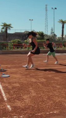 Bayan eğitmen, gündüz vakti Clay Court 'ta tenis öğretiyor..