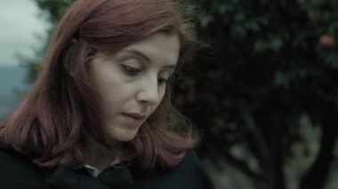 Bulutlu bir günde kırsalda pelerinli genç bir kadın..