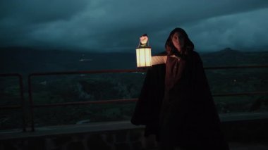 Bulutlu bir günde kırsalda pelerinli genç bir kadın..