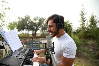 Beyaz gömlekli çocuk dışarıdaki doğada piyano çalıyor..