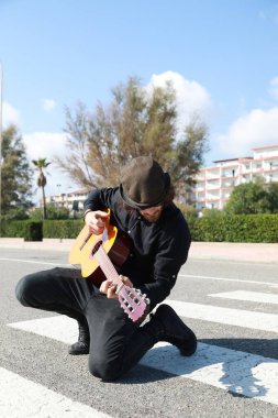 Genç adam, yazın yaya geçidinde gitar çalıyor..