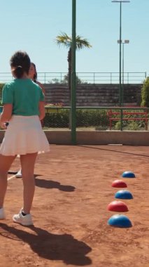 Bayan eğitmen, gündüz vakti Clay Court 'ta tenis öğretiyor..