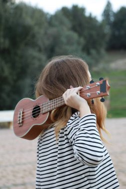Mutlu kız doğada gitar çalıyor..