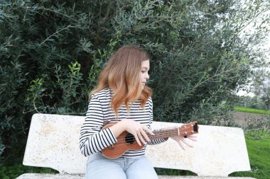 Mutlu kız doğada gitar çalıyor..