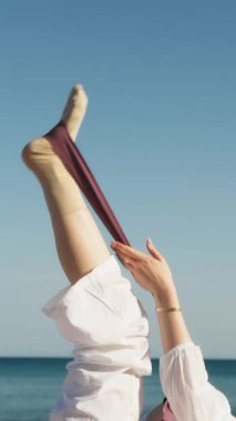 Yazın plajda beyazlar içinde dans eden genç bir kadın.