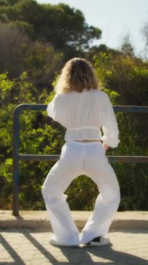 Yazın plajda beyazlar içinde dans eden genç bir kadın.