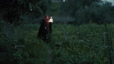Bulutlu bir günde kırsalda pelerinli genç bir kadın..