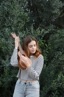 Mutlu kız doğada gitar çalıyor..