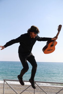 Gitar Müzisyeni Okyanus Kıyısındaki Korkuluklarda Dengeleniyor.