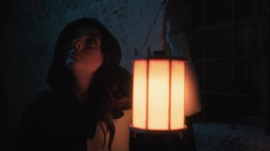 Gizemli genç kadın pelerin ve fenerle bir köyün sokaklarında yürüyor..
