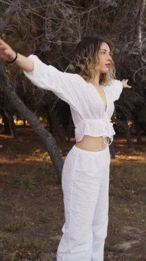 Yazın plajda beyazlar içinde dans eden genç bir kadın.