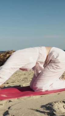 Yazın plajda beyazlar içinde dans eden genç bir kadın.