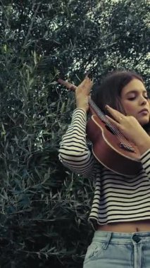 Mutlu kız doğada gitar çalıyor..