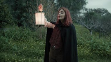 Bulutlu bir günde kırsalda pelerinli genç bir kadın..