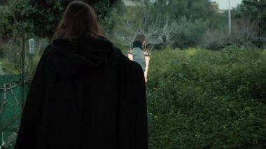 Bulutlu bir günde kırsalda pelerinli genç bir kadın..