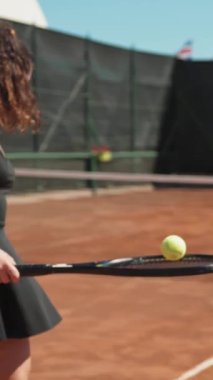 Bayan eğitmen, gündüz vakti Clay Court 'ta tenis öğretiyor..