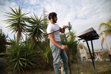 Beyaz gömlekli çocuk dışarıdaki doğada piyano çalıyor..