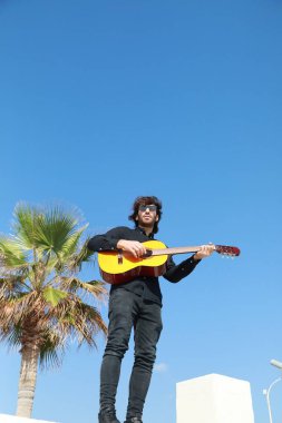 Adam parktaki bir günlük ayakta klasik gitar çalıyor..