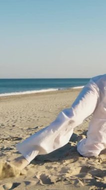 Yazın plajda beyazlar içinde dans eden genç bir kadın.