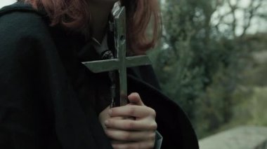 Bulutlu bir günde kırsalda pelerinli genç bir kadın..