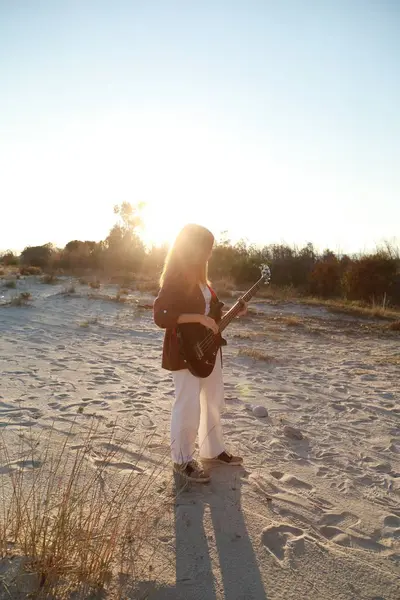 Sahilin yanındaki doğada bas gitar çalan bir kız..