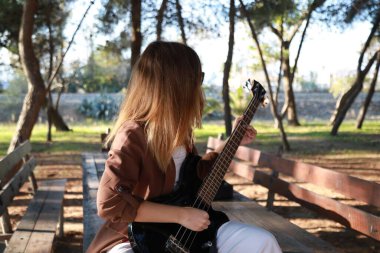 Sahilin yanındaki doğada bas gitar çalan bir kız..