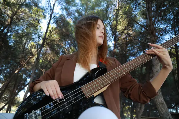 Sahilin yanındaki doğada bas gitar çalan bir kız..