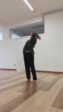 Spor salonunda siyah eşofmanlı bir kadın spor modunda dans ediyor..