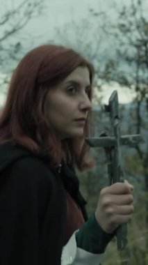 Bulutlu bir günde kırsalda pelerinli genç bir kadın..