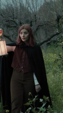 Bulutlu bir günde kırsalda pelerinli genç bir kadın..