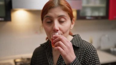 Kadın bardakta çay tadıyor ve evinde gülüyor..