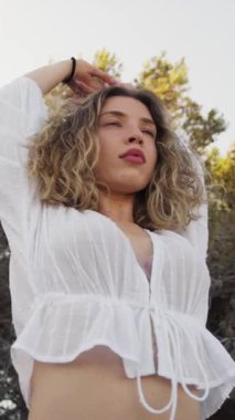 Yazın plajda beyazlar içinde dans eden genç bir kadın.