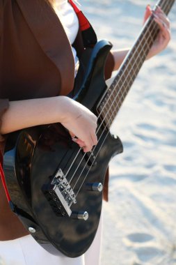 Sahilin yanındaki doğada bas gitar çalan bir kız..