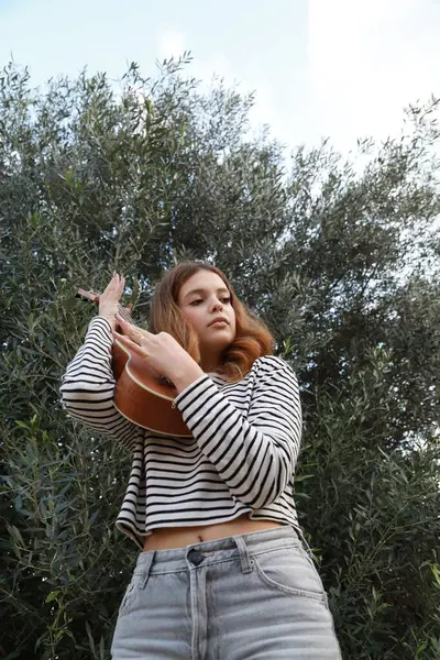 Mutlu kız doğada gitar çalıyor..