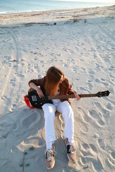 Sahilin yanındaki doğada bas gitar çalan bir kız..