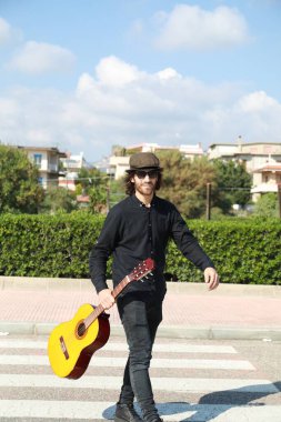 Genç adam, yazın yaya geçidinde gitar çalıyor..