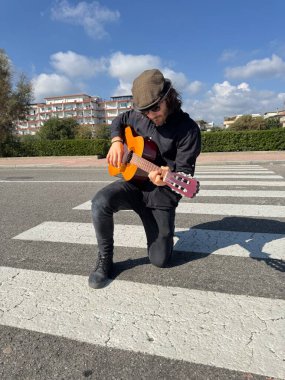 Genç adam, yazın yaya geçidinde gitar çalıyor..