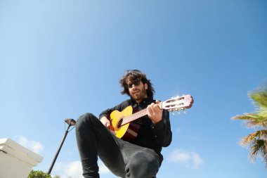 Adam parktaki bir günlük ayakta klasik gitar çalıyor..