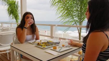 Calabria 'daki tatil köyünde yiyip içen genç kadınlar. .