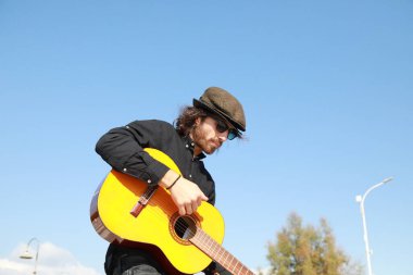 Genç adam, yazın yaya geçidinde gitar çalıyor..