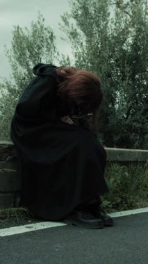 Bulutlu bir günde kırsalda pelerinli genç bir kadın..