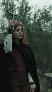 Bulutlu bir günde kırsalda pelerinli genç bir kadın..